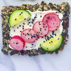 savoury topped seed cracker on a marble background.
