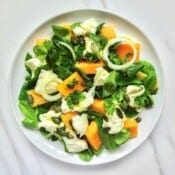 melon caprese salad on a white plate.
