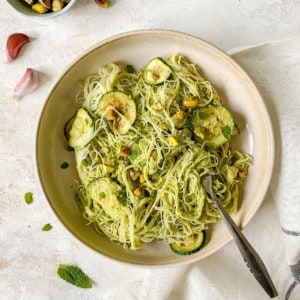 pistachio, zucchini and mint rice noodles in a brown bowl.