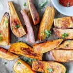 sweet potato wedges on a baking tray next to a small bowl of paprika.