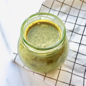pumpkin seed butter in a glass jar on a checked cloth.