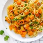 white plate of brown butter butternut squash pasta on a check cloth.