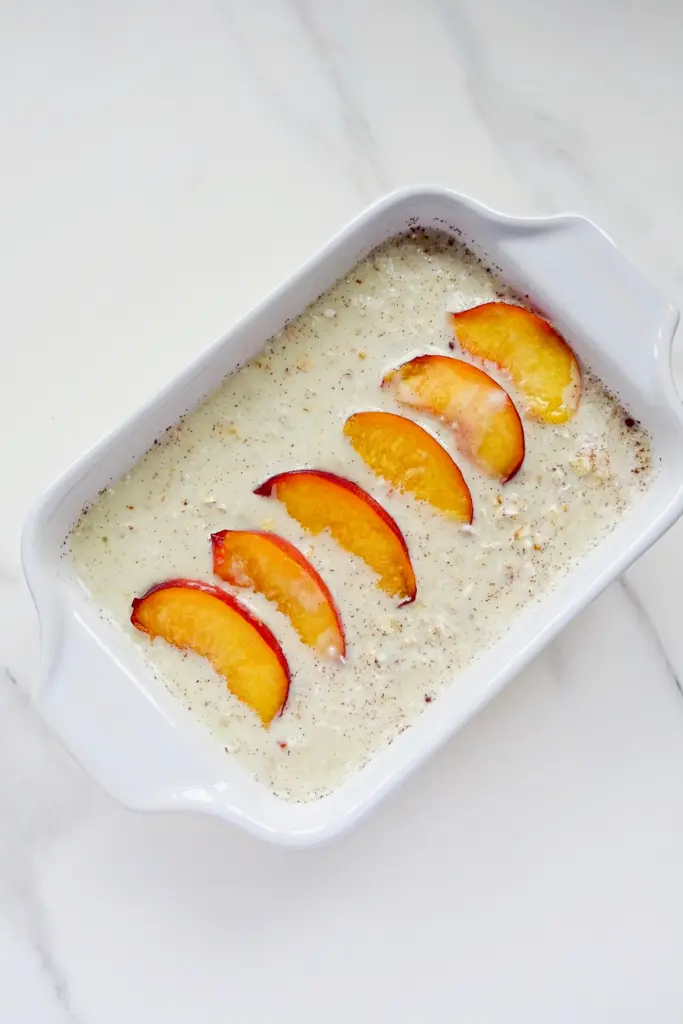 oats, milk and peaches in a white dish.