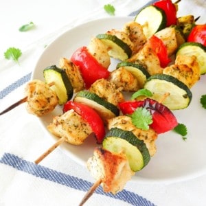 coconut chicken skewers on a white plate.