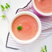 two bowls of pomegranate posset on a striped cloth.