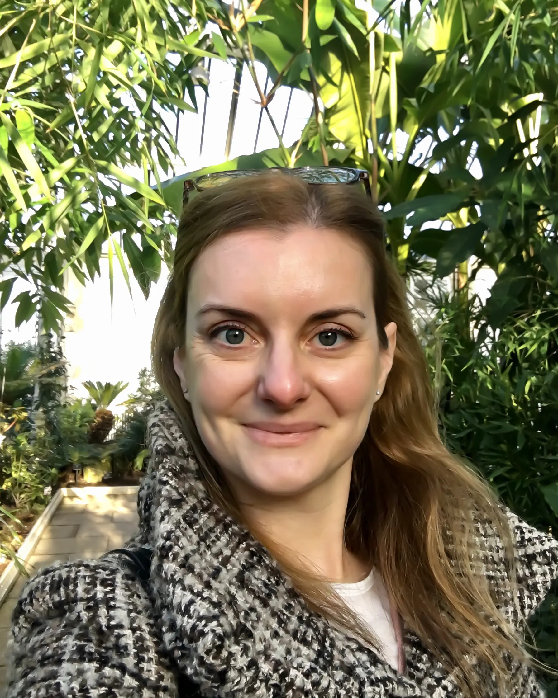 a woman in a greenhouse wearing a tweed coat.