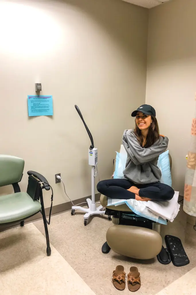 woman in a hospital room giving herself a hug.