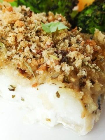 close up of Italian herb crusted cod on a white plate.