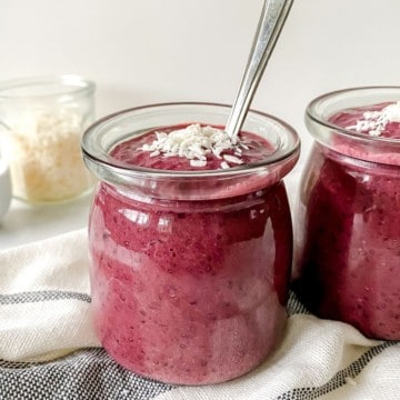 cherry chia pudding in a glass jar with a spoon in it.