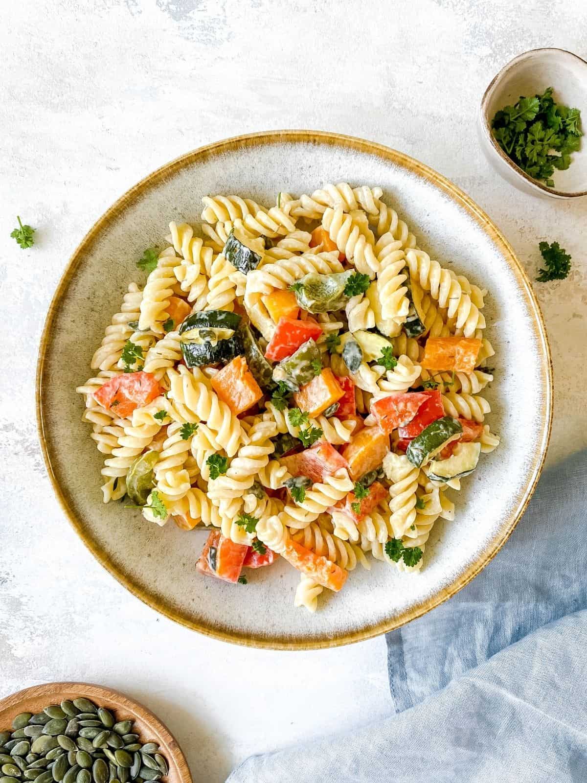 roasted vegetable pasta salad in a grey bowl on a blue linen cloth.