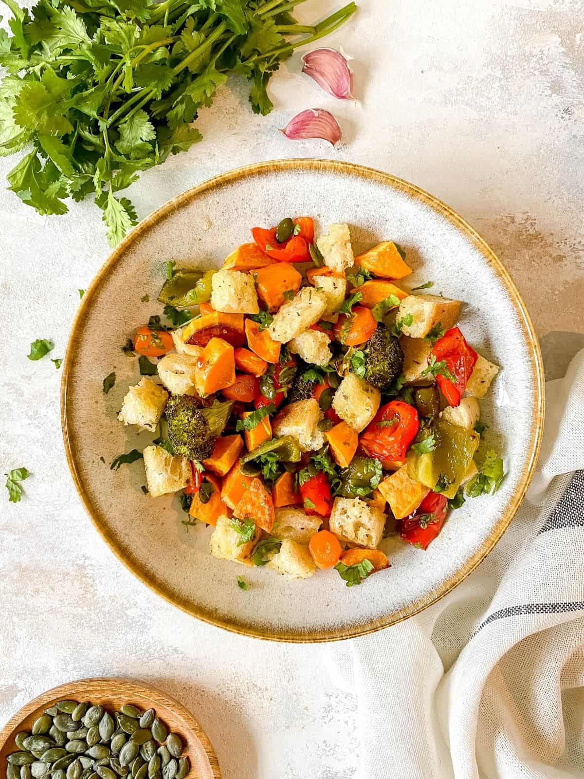 roasted vegetable panzanella salad in a grey bowl.