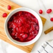 citrus free cranberry sauce in a white bowl on a wooden board.
