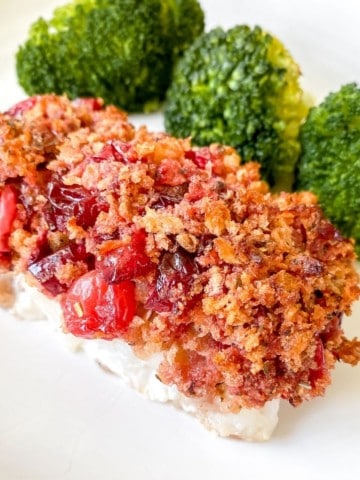 cranberry crusted cod and broccoli on a white plate.