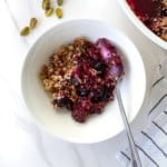 white bowl of blueberry and blackberry crisp with a spoon in it next to a dish of blackberry crisp.