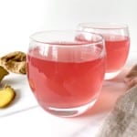 two glasses of pomegranate ginger tea next to a beige cloth.