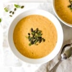 two white bowls of vegan cauliflower corn chowder next to spoons.