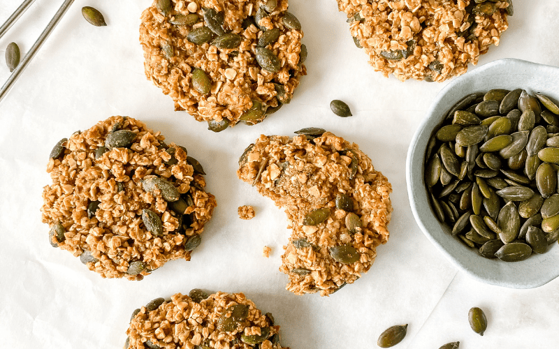 cardamom oat cookies with a bowl of pumpkin seeds next to them.