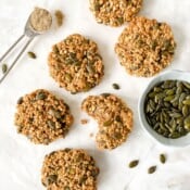 cardamom oatmeal cookies with a spoonful of cardamom and a bowl of seeds next to them.