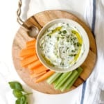 overhead view of whipped ricotta dip in a bowl on a wooden chopping board.