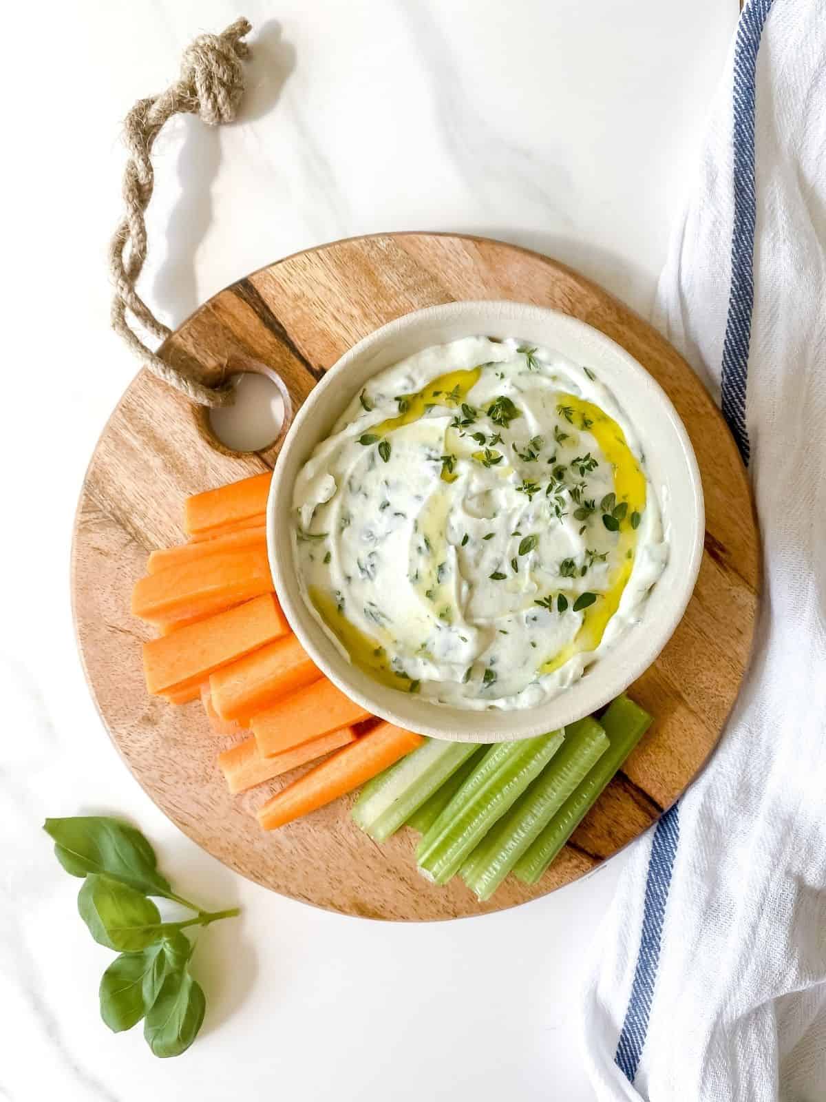 whipped ricotta dip with honey and herbs in a white bow on a chopping board.