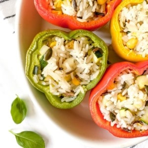 wild rice stuffed peppers in a white baking dish.