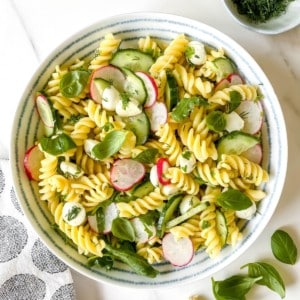 cucumber dill pasta salad in a white bowl with a blue striped rim.