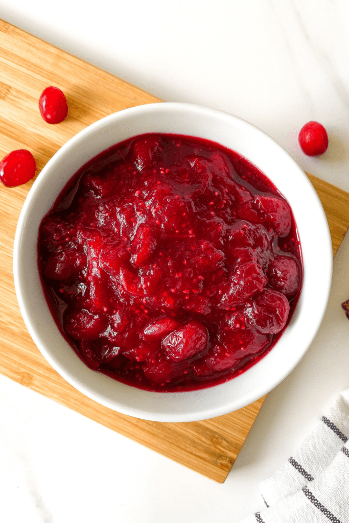 cranberry sauce in a white bowl on a wooden board