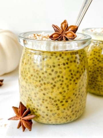 pumpkin spice chia pudding in a glass jar with a white pumpkin in the background.