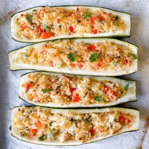 four quinoa stuffed zucchini boats on a baking tray.