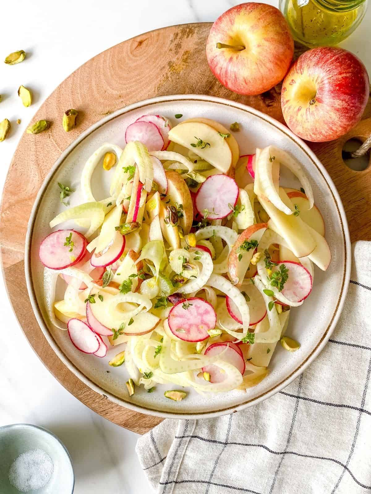 apple, fennel and radish salad on a brown plate.