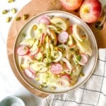 apple, fennel and radish salad on a brown plate on a wooden board.