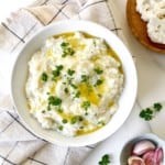 white bowl of mashed cauliflower with cream cheese on a checked tea towel.