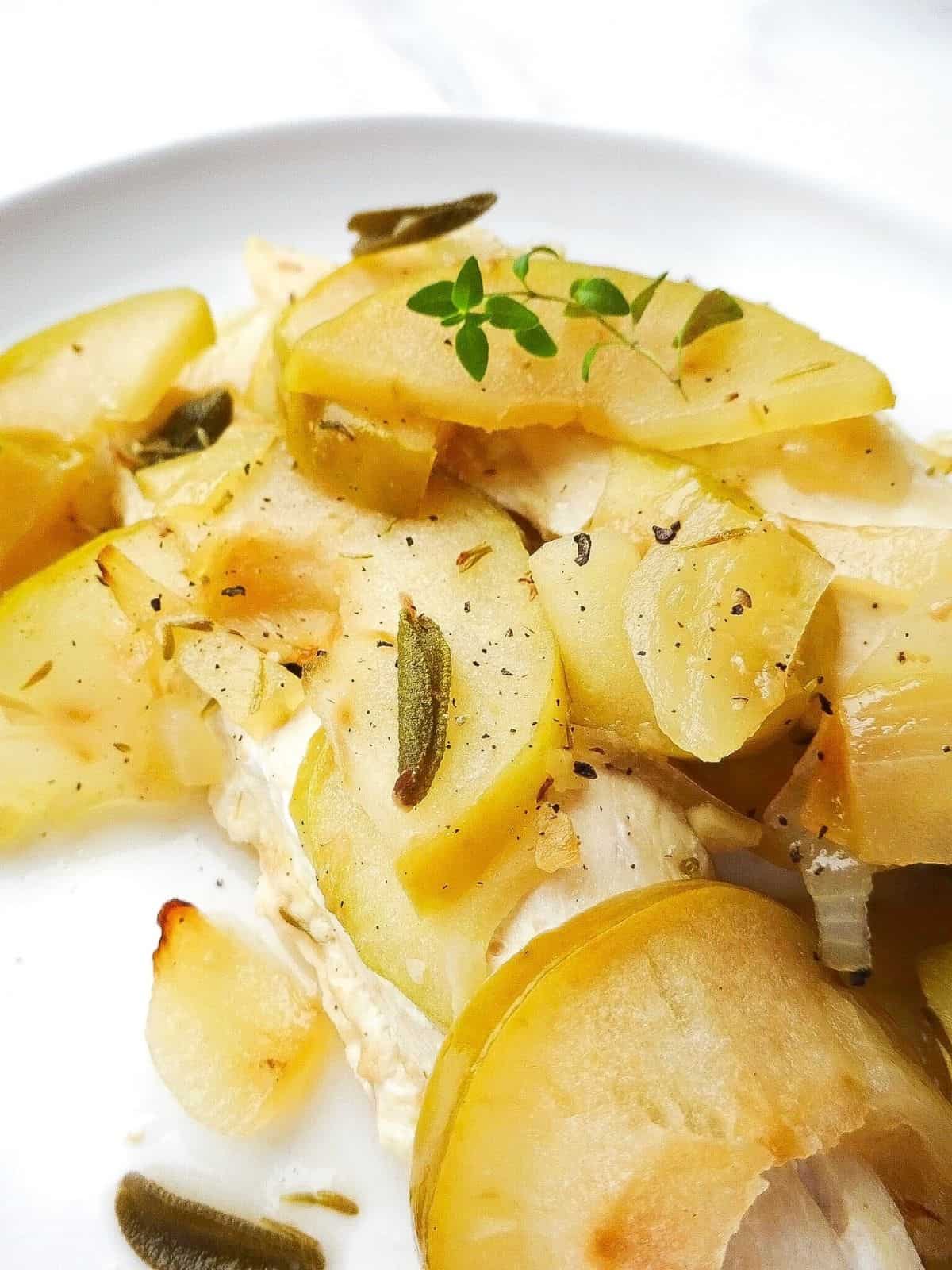 baked chicken with apples and honey on a white plate garnished with herbs