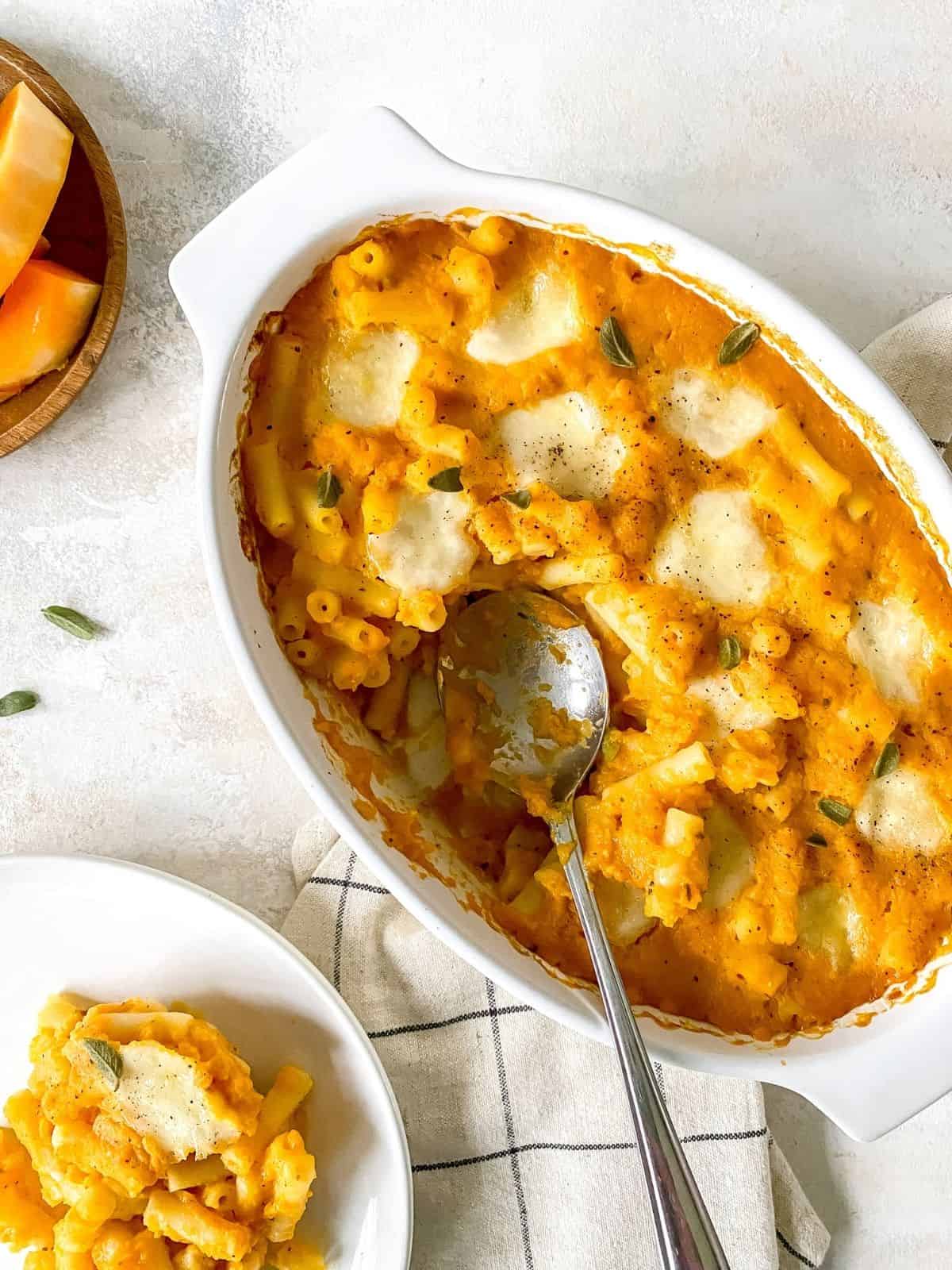butternut squash pasta bake in a white dish with a spoon in it.