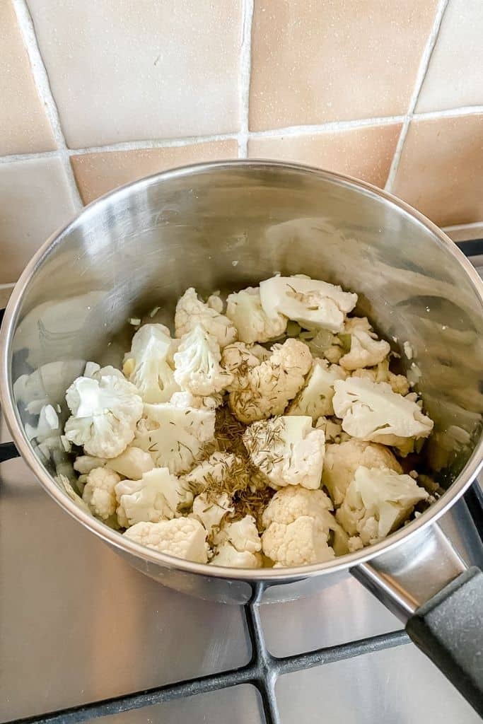 cauliflower florets in a pan on a stove top.