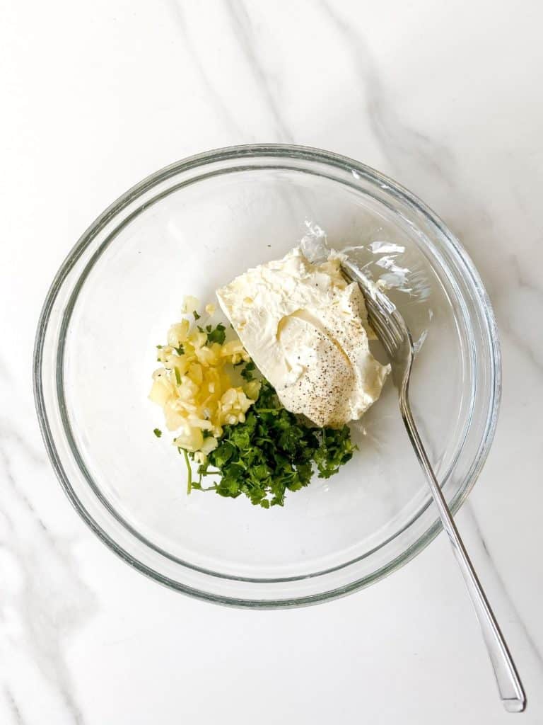 cream cheese, onion and herbs in a glass bowl.