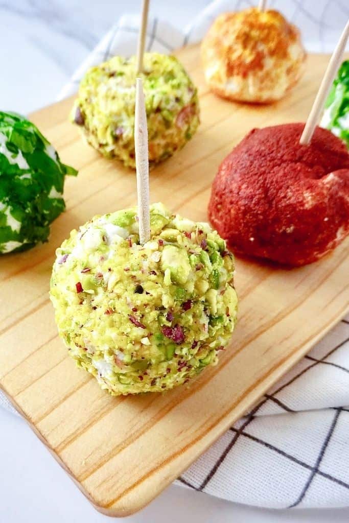 herbed ricotta cheese balls with toothpicks in them on a wooden chopping board.
