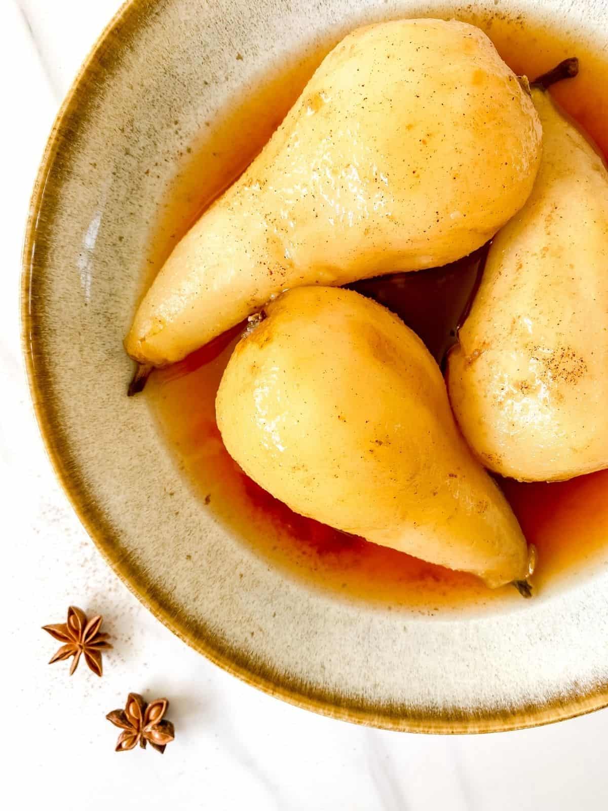 poached pears in a grey and brown bowl.