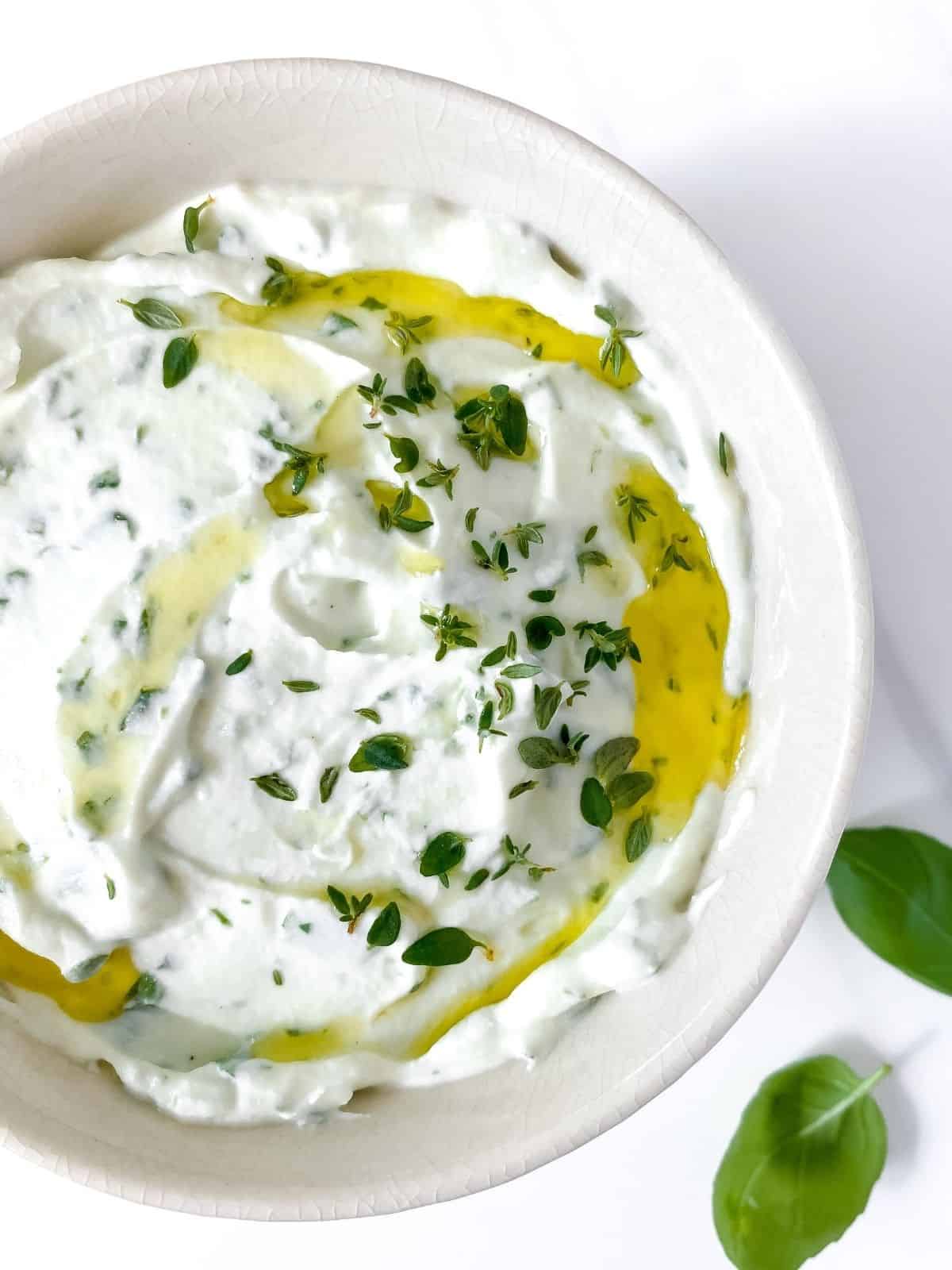 whipped ricotta dip with herbs and honey in a white bowl.