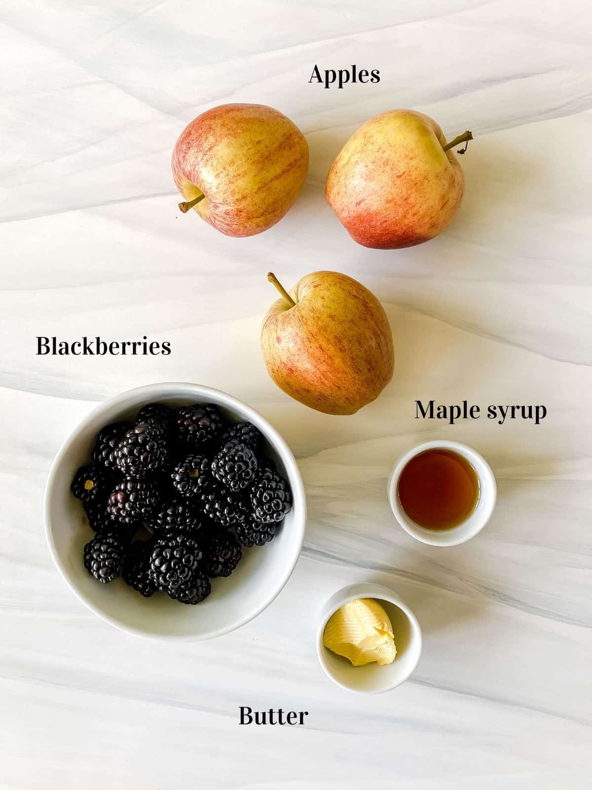 three apples and bowls of blackberries, maple syrup and butter.