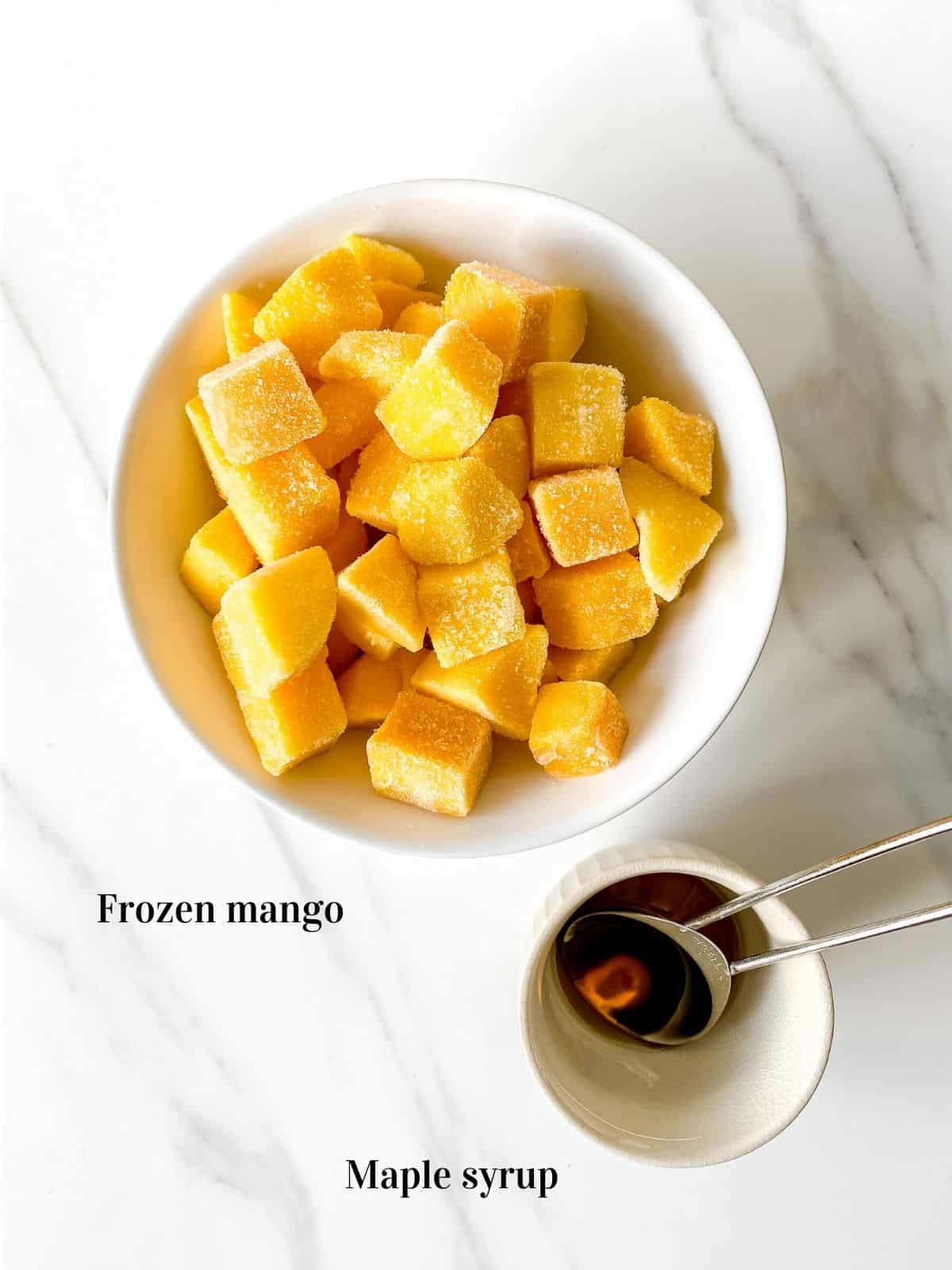 individually labelled bowl of frozen mango with a smaller bowl of maple syrup.