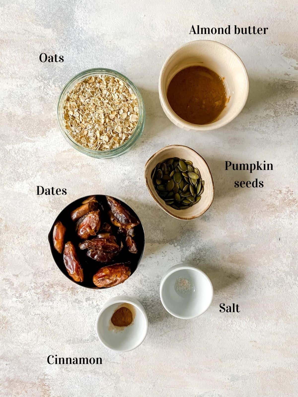 oats, almond butter, pumpkin seeds, dates, salt and cinnamon in small bowls.