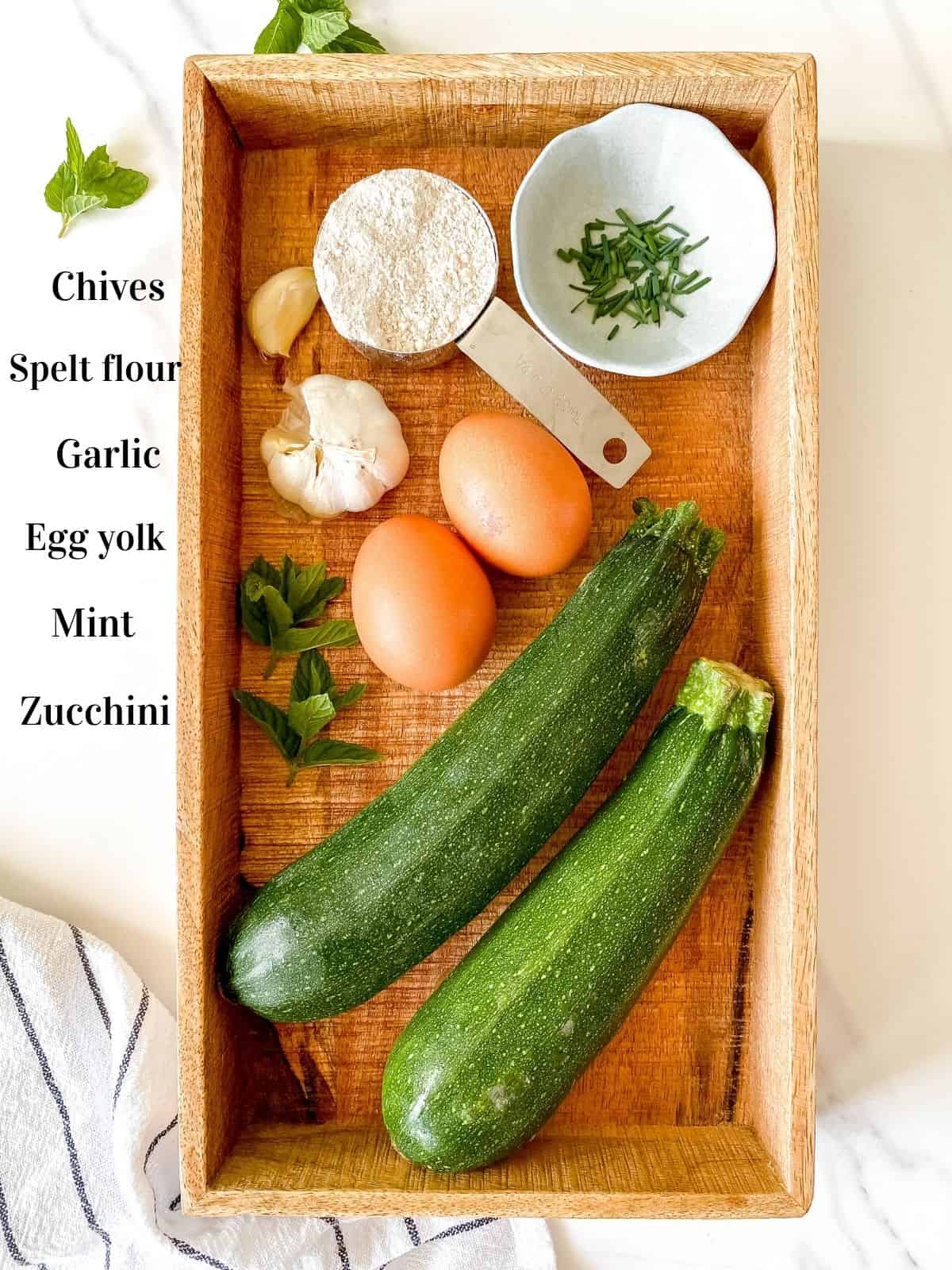 wooden box containing labelled zucchini, mint, garlic, chives, spelt flour and eggs.