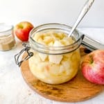 apple and pear compote in a glass jar with a spoon in it.
