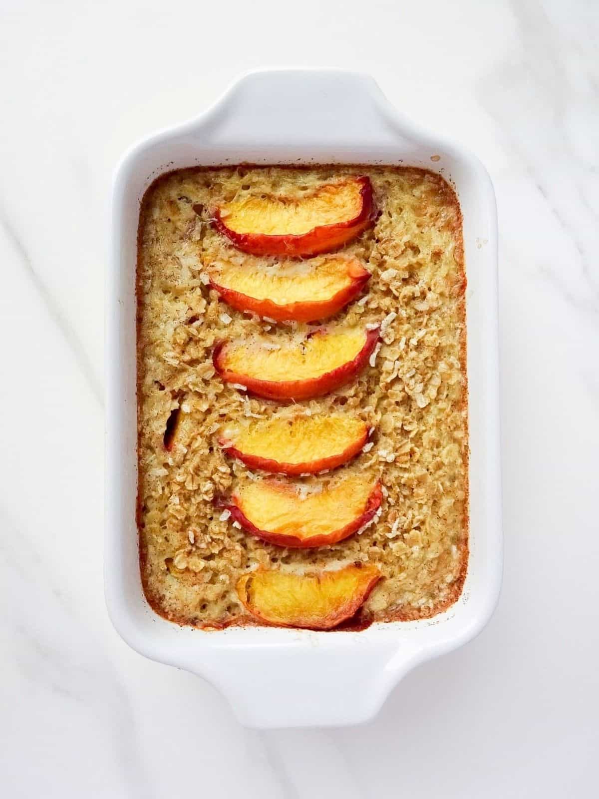 baked peach oatmeal in a white dish.