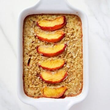 baked peach oatmeal in a white dish.