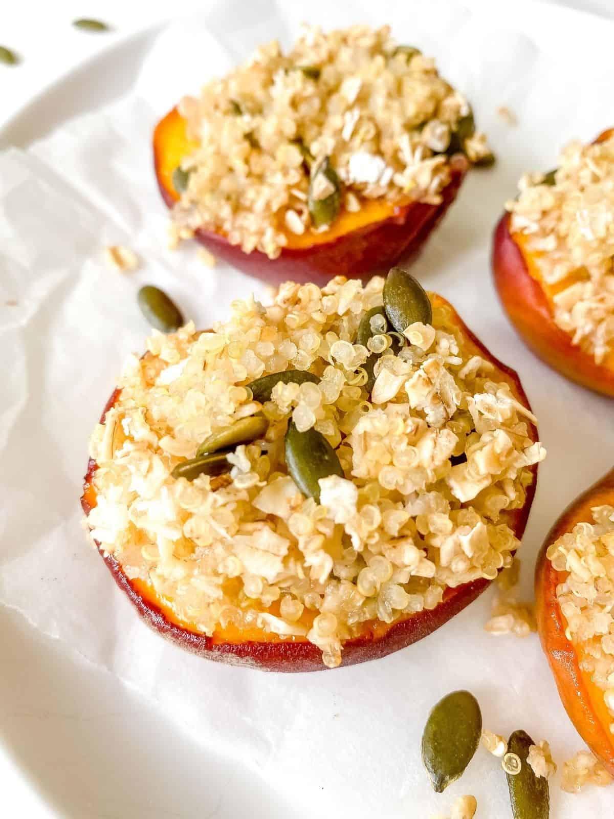 baked peaches with a crumble topping on a white plate.
