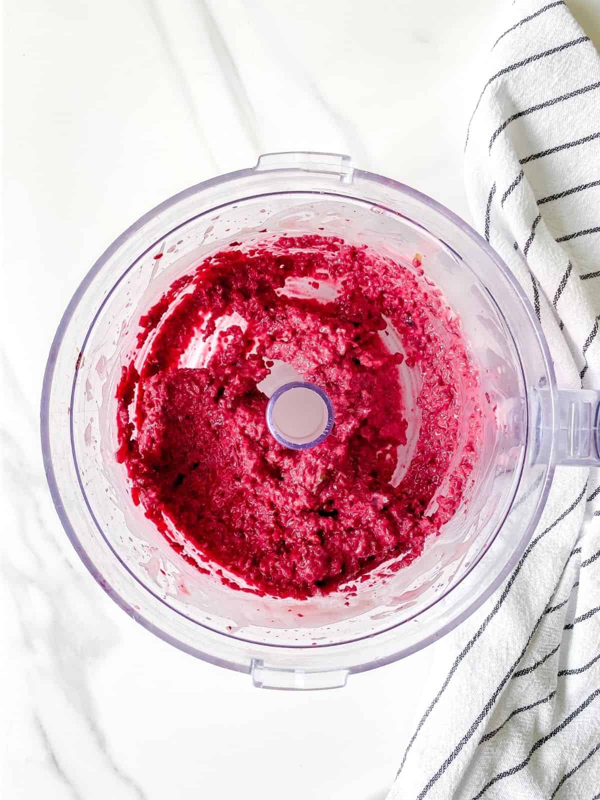 blended beets in a blender next to a white and black striped cloth.