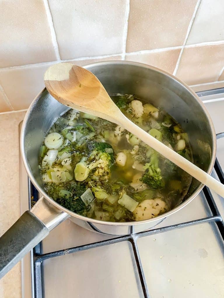 broccoli and cauliflower in a pan with a spoon on it.