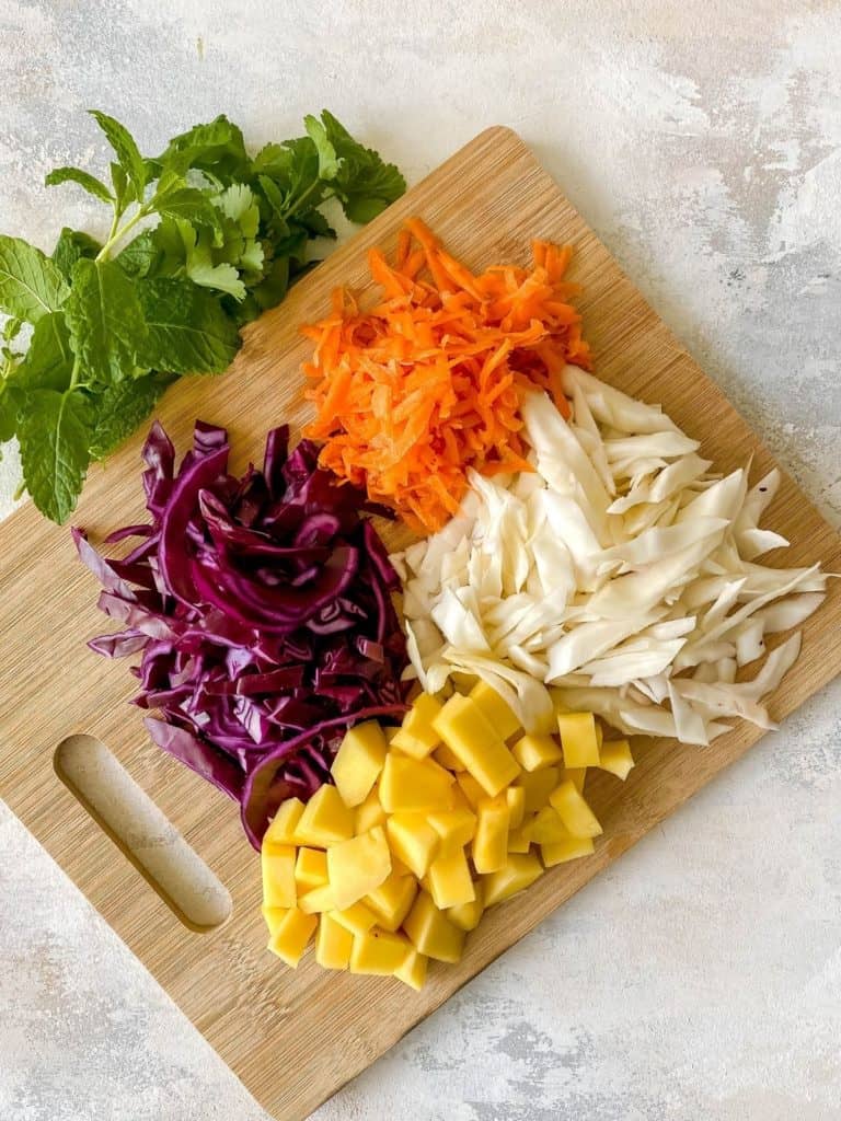 diced cabbage, carrot and herbs on a wooden board.